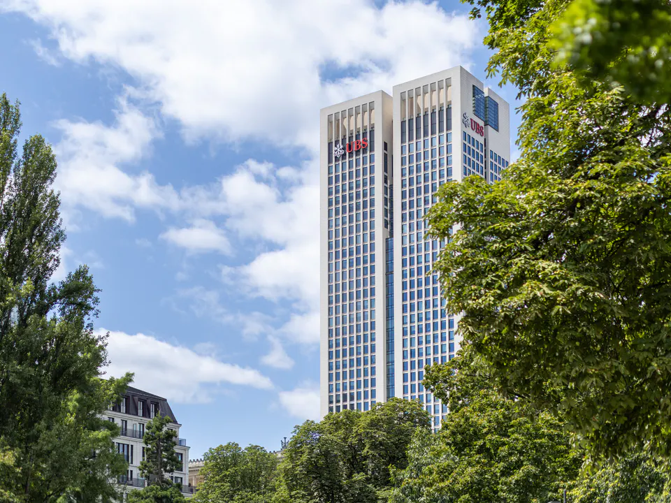 OpernTurm in Frankfurt, eingerahmt von grünen Bäumen